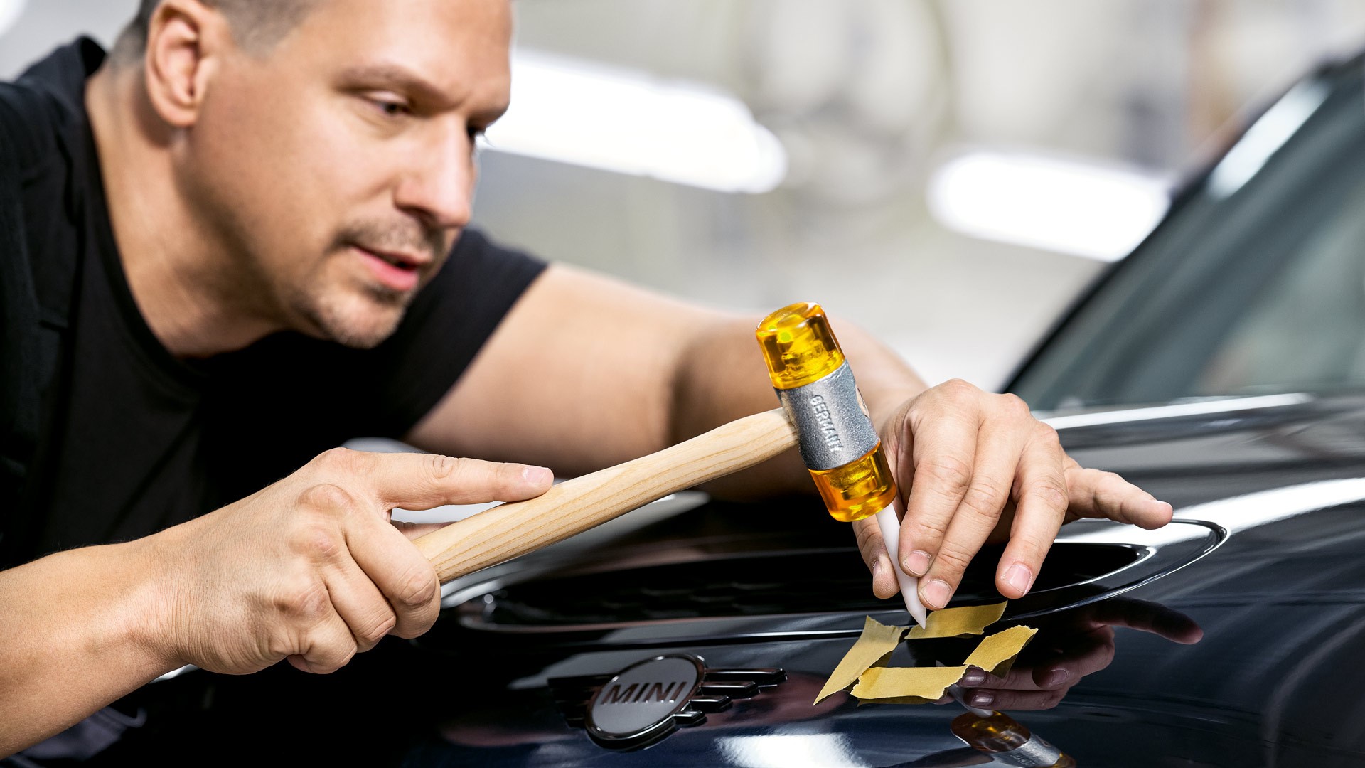 Technician aligns bonnet panel on a Midnight Black II MINI.
